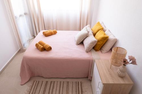 a small bedroom with a pink bed with yellow pillows at Charming Apartment with Balcony - Heart of Los Cristianos in Arona