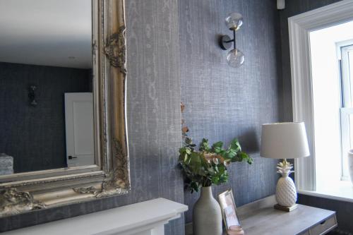 a mirror on a wall next to a table with a lamp at Luxury Croft Templepatrick Near Airport Rabbit and Hilton hotel in Templepatrick