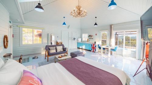 a bedroom with a bed and a living room at Arasol Pension in Geoje 
