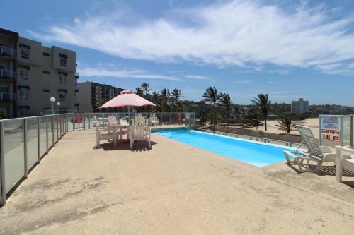 a pool with chairs and an umbrella next to a building at Seagull 312 in Margate
