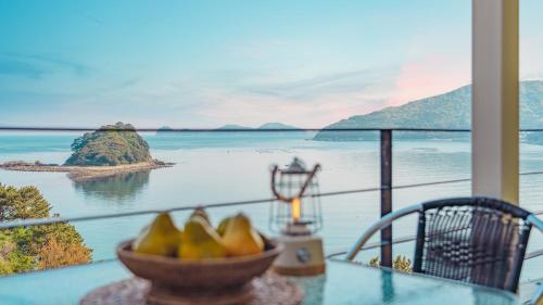 a bowl of fruit on a table with a view of the ocean at Arasol Pension in Geoje 