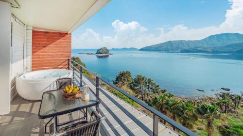 a balcony with a bath tub and a view of the water at Arasol Pension in Geoje 