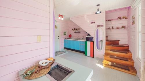 a room with a kitchen with pink walls and a staircase at Arasol Pension in Geoje 