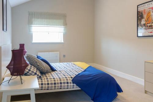 ein Schlafzimmer mit einem Bett mit einer blauen Decke und einem Fenster in der Unterkunft Beautiful New 2 Bed Flat - 5 August House in London