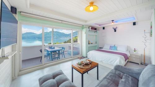 a bedroom with a bed and a view of the ocean at Arasol Pension in Geoje 