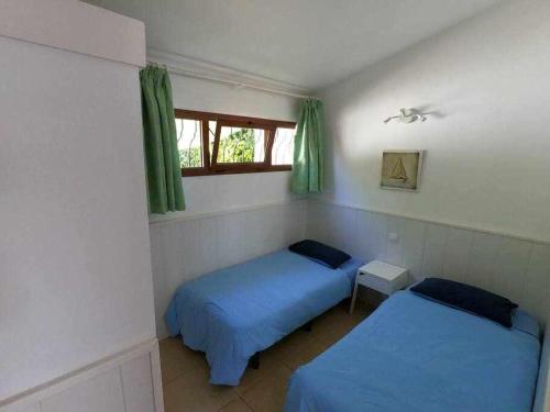 1 dormitorio con 2 camas y una ventana con cortinas verdes en Acogedor Bungalow en Playa del Inglés, en Playa del Inglés