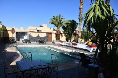 a swimming pool with chairs and a table in front of a building at Hôtel La Vallée Des Oiseaux in Boumalne