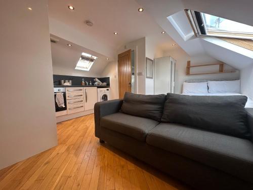 a living room with a couch and a kitchen at Stanningley Studio in Farsley