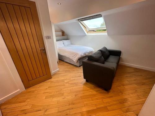 um quarto com um sofá, uma cama e uma janela em Stanningley Studio em Farsley