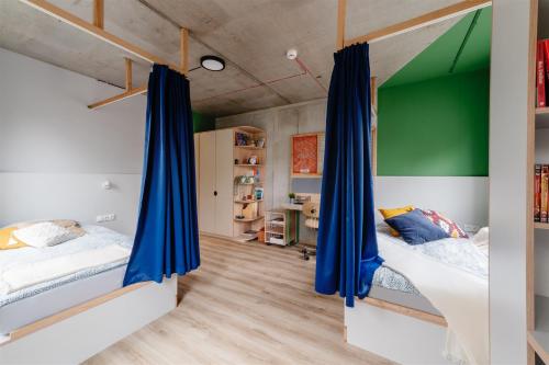 two beds in a room with blue curtains at Chillout Dorm Cracow by BookingHost in Krakow