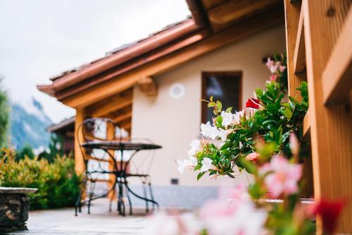 a patio with a table and chairs and flowers at De Goldene Traum in Gressoney-Saint-Jean