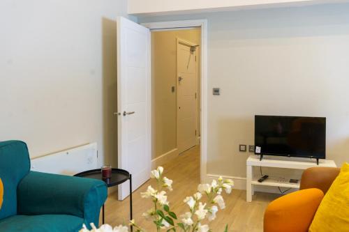 a living room with a blue couch and a television at Stunning New 2 Bed Flat - 6 August House in London