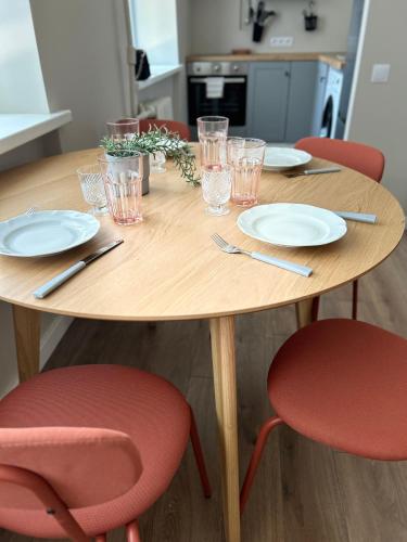 a wooden table with red chairs and plates and glasses at Skandi Appartments in Saldus city center in Saldus