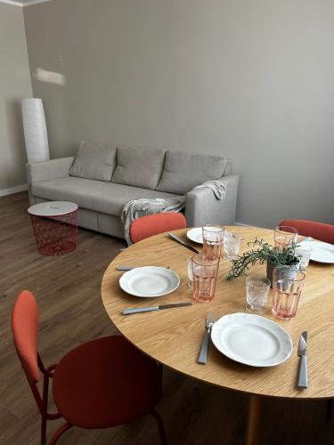 a wooden table with plates and utensils in a living room at Skandi Appartments in Saldus city center in Saldus