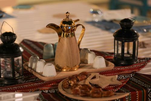 Nozol Al Rayaheen By Sharjah Collection في خور فكان: طاولة مع غلاية الشاي وصحن من الطعام