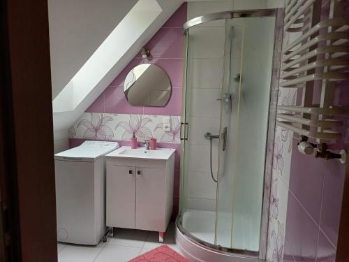 a pink bathroom with a sink and a shower at Pełny Relaks - Sajenek in Augustów