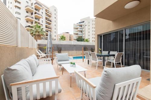 un patio al aire libre con muebles, mesa y sillas en O&O Group - Prestigious Beachfront Villa W Private Pool, en Rishon LeZion