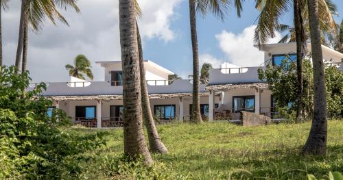 a building with palm trees in front of it at Pingwe Beach Apartments in Pingwe