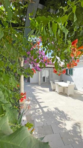 a patio with flowers and a table and chairs at Villa Ardura - island holiday residence **** Bol. Island Brač in Bol