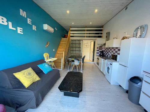 un salon avec un canapé et une cuisine dans l'établissement Les Mouettes, à Les Sables-dʼOlonne