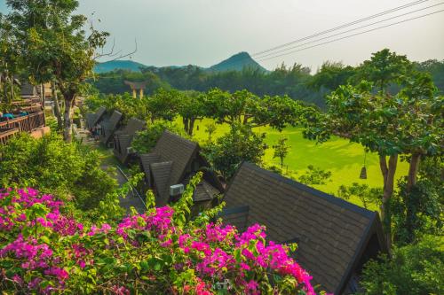 a row of houses with pink flowers and a field at Suan Sai Yok Resort in Sai Yok