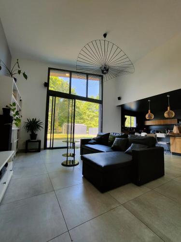 un salon avec un canapé noir et une cuisine dans l'établissement Maison moderne a 1km du circuit des 24h du mans, à Arnage