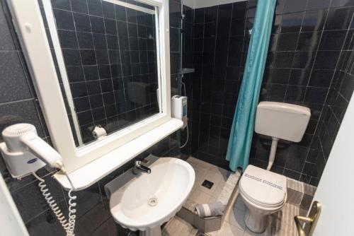 a bathroom with a toilet and a sink and a window at Hotel Magdalena in Pefkohori