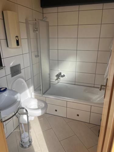 a bathroom with a toilet and a tub and a sink at Bungalow Nordschwarzwald im Ferienpark Schellbronn in Neuhausen