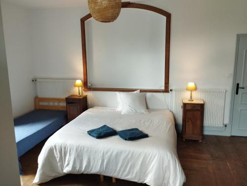 a bedroom with a bed with two blue pillows on it at Chambres d'hôtes l'arche d'Yvann in Campuac