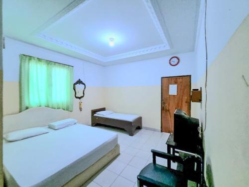 een slaapkamer met 2 bedden, een stoel en een raam bij Hotel Taman Sari in Jakarta