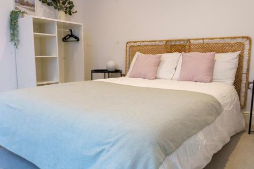 1 dormitorio con 1 cama grande con almohadas rosas y blancas en Gorgeous New 2 Bed Flat - 2 August House, en Londres