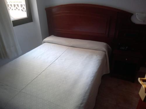a bedroom with a bed with a wooden headboard at Hotel Tropical in Puerto de la Cruz