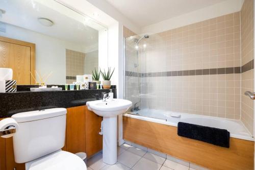 a bathroom with a toilet and a sink and a tub at Lovely 2 BR apartment with balcony in Dublin