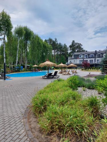 um pátio com guarda-sóis e cadeiras ao lado de uma piscina em Apartament Bursztyn em Pobierowo