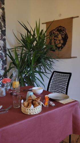 a table with a red table cloth with a basket of bread at Chambre d'hôtes LE FLACON DE LA VERROUILLE in Bruniquel