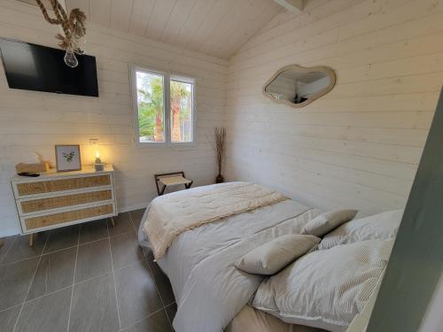 um quarto com uma cama, uma cómoda e uma televisão em La Cabane de l'Estran au bord de mer em Lanton