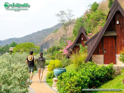 two people walking down a path in front of a house at Suan Sai Yok Resort in Sai Yok