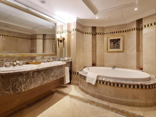 a large bathroom with two sinks and a tub at Corniche Hotel Sharjah in Sharjah
