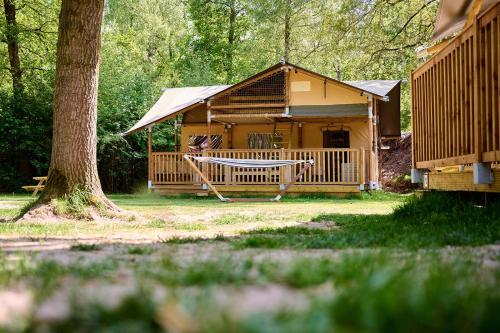 a log cabin with a porch and a tree at Glamping Renswoude in Renswoude