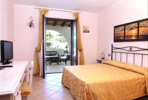a bedroom with a bed and a television and a patio at Hotel Borgo Eolie in Lipari