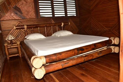 a bedroom with a bed in a wooden room at LOCAVACATION Les Hauts Manguiers Villa 15 in Ambondrona