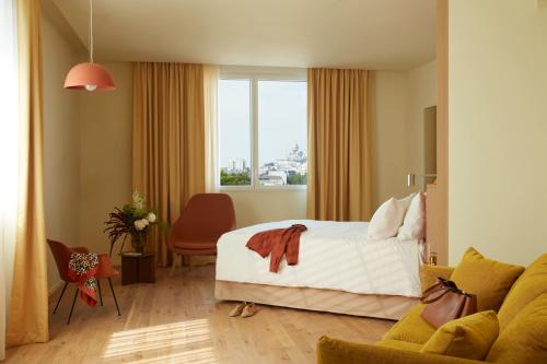パリにあるOKKO Hotels Paris Rosa Parksのベッドとソファ付きのホテルルーム