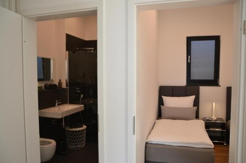 - une chambre avec un lit, un lavabo et un miroir dans l'établissement Bergweide 36, à Sasbachwalden