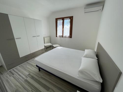 a white bedroom with a bed and a window at VILLA SALICE 9.2 in Isola Albarella