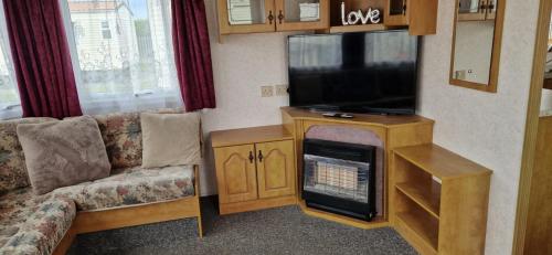 a living room with a couch and a flat screen tv at 2 bed 36 Highbury park Skegness ingoldmells caravan in Ingoldmells