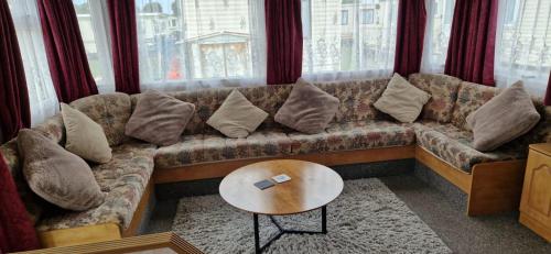a living room with a couch with pillows and a table at 2 bed 36 Highbury park Skegness ingoldmells caravan in Ingoldmells
