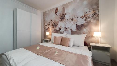 - une chambre avec un grand lit orné de fleurs sur le mur dans l'établissement Villa Napsugár, à Balatonlelle