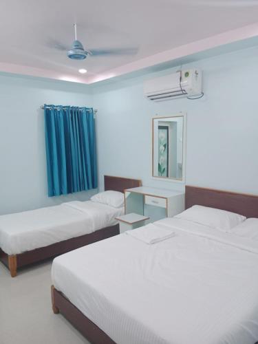a bedroom with two beds and a blue curtain at KN residency, near Trichy Airport in Tiruchchirāppalli