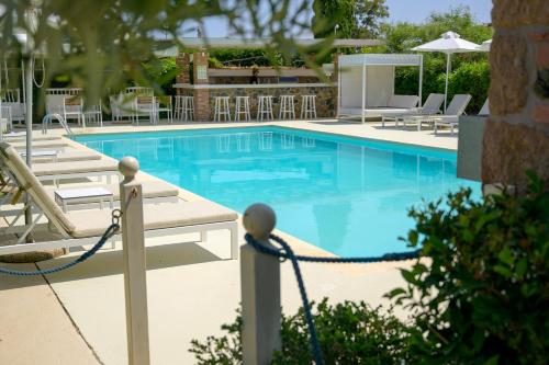 a large swimming pool with chairs and a table at Oikies Small Elegant Houses in Mytilini