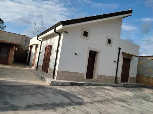 een wit gebouw met bruine deuren op een straat bij Villa Falconara in Noto